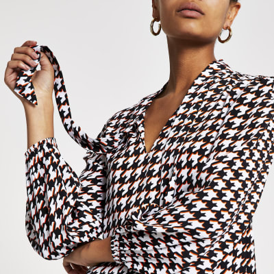 Zwarte blouse met pied-de-poule-motief en strik bij de hals