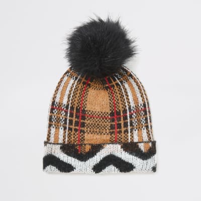 Beige geruite en gebreide muts van imitatiebont met pompon