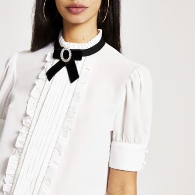 Witte blouse verfraaide met strik en ruches